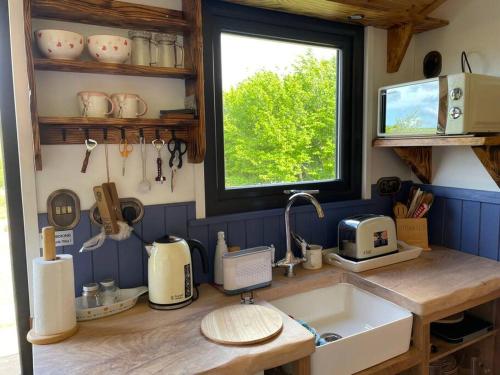 a kitchen counter with a sink and a window at Pembrokeshire Shepherd hut with hottub in Jordanston