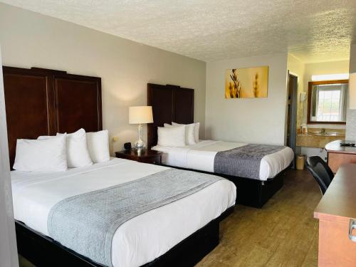a hotel room with two beds and a table at Days Inn by Wyndham Fort Walton Beach in Fort Walton Beach