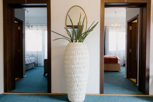 a large white vase with a plant in a room at Excelsior INN in Turda