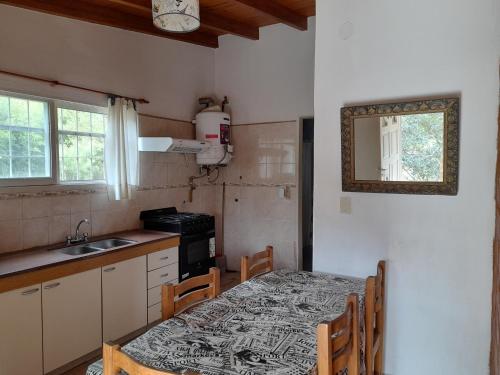 a kitchen with a table and a sink and a table and chairs at Cabañas Aliksir in Cosquín