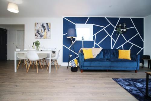 a living room with a blue couch and a table at Casa di pietra - Cardiff City centre apartment with patio, Free private parking in Cardiff