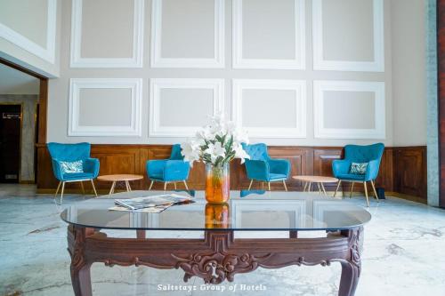 a room with a glass table and blue chairs at Saltstayz Premier - Cyber Hub in Gurgaon