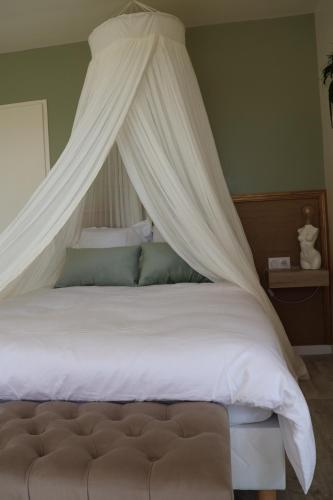 een slaapkamer met een hemelbed met witte lakens en kussens bij Les gîtes coquins in Amilly