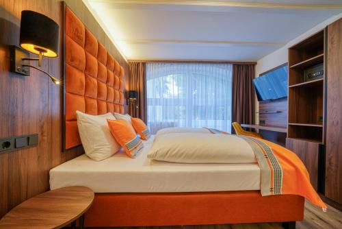a bedroom with a large bed with an orange headboard at Zentrum Hotel Stade in Stade