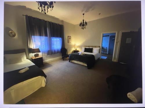 Habitación de hotel con 2 camas, 1 cama y 1 silla en St Andrews house Hotel, en Preston