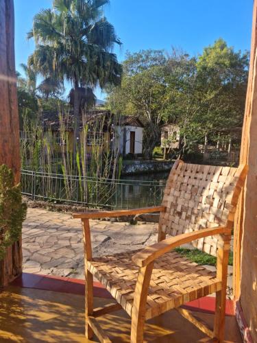 a wooden chair sitting on a porch with a palm tree at Pousada Cipó Artes in Prados