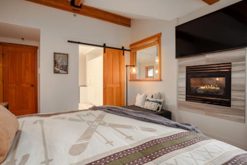 ウィスラーにあるLuxury Mountain Retreat with PRIVATE Hot Tub by Harmony Whistlerのベッドと暖炉のある寝室