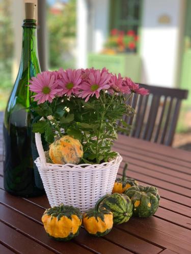 a flower arrangement in a basket on a table with a bottle at Pannonhalma Várlak Vendégház in Pannonhalma