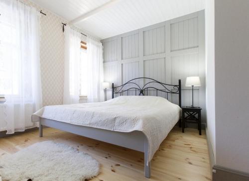 a bedroom with a bed with a white bedspread and a rug at Ösel Apartment in Kuressaare