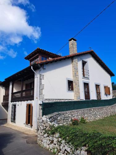 a white house with a stone wall at D´Eloisa in Balmori