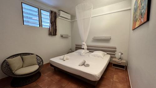 a bedroom with a bed and a chair and a window at La Pagerie, joli bas de villa avec piscine au calme à 5 minutes de la plage in Les Trois-Îlets