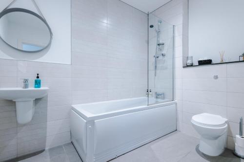 La salle de bains blanche est pourvue d'une baignoire, de toilettes et d'un lavabo. dans l'établissement Victoria Mill by Staycay, à Wigan