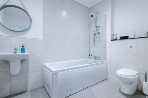 a white bathroom with a tub and a toilet and a sink at Victoria Mill by Staycay in Wigan