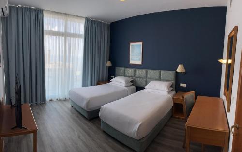 duas camas num quarto de hotel com paredes azuis em El Sheikh Suites Hotel em Beirute