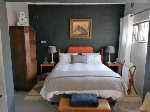 Pied Cow Cottage في هيلتون: غرفة نوم مع سرير وطاولتين مع مصابيح