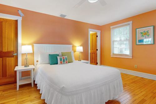 a bedroom with a large white bed and orange walls at Baya House in Key West