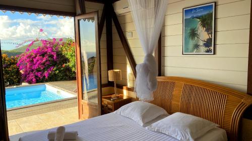 um quarto com uma cama e vista para uma piscina em Villa de charme avec piscine et magnifique vue mer em Les Anses-dʼArlets