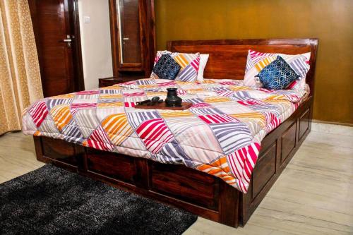 a bed with a wooden frame with a colorful comforter at Atithi Stay By Kasa Lusso - Luxury 2 BHK In Faridabad in Faridabad