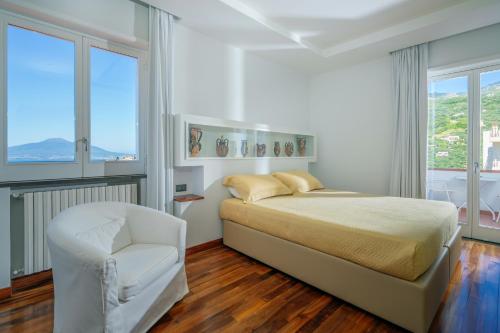 una camera bianca con un letto e una sedia di Villagraziosa a Vico Equense