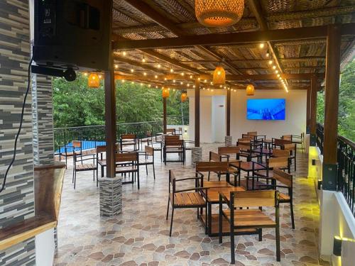 a restaurant with wooden tables and chairs and a screen at AKUAIPPA HOSTAL RESTAURANT in Santa Marta