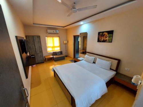 a bedroom with a large white bed and a window at Gir Jungle Lodge in Sasan Gir