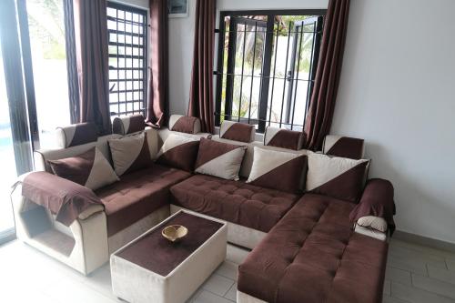 a large couch in a living room with windows at 3 Bedroom Family Pool Villa Flic-en-Flac Beach in Flic-en-Flac