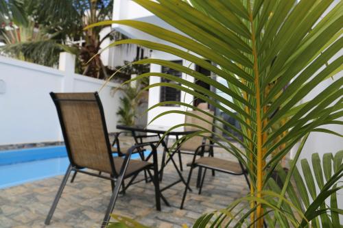 a patio with chairs and a palm tree next to a pool at 3 Bedroom Family Pool Villa Flic-en-Flac Beach in Flic-en-Flac