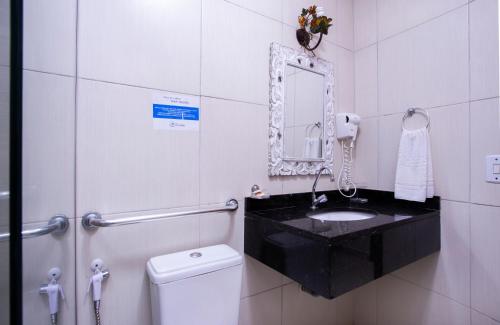 a bathroom with a sink and a mirror and a toilet at Hotel Village Enseada in Ubatuba