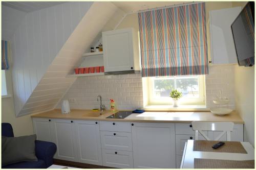 Neringa的住宿－Vila Preila，厨房配有白色橱柜、水槽和窗户。
