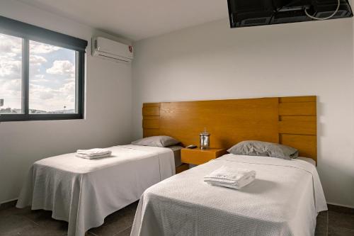Habitación con 2 camas con sábanas blancas y ventana en Coyotes Housing Services 
