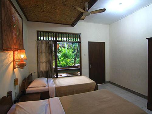 a bedroom with two beds and a window at Dewa Bharata Bungalows Candidasa in Candidasa