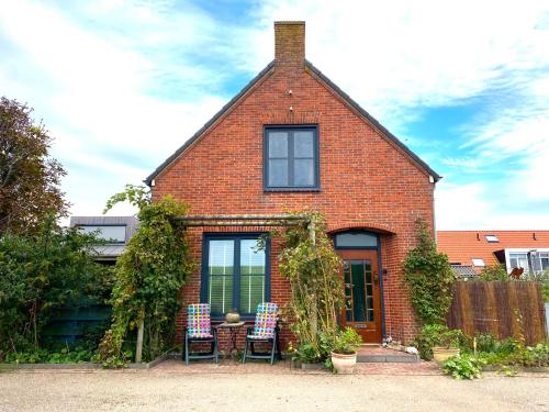 a brick house with two chairs and a table at Philipstère in Sint Philipsland