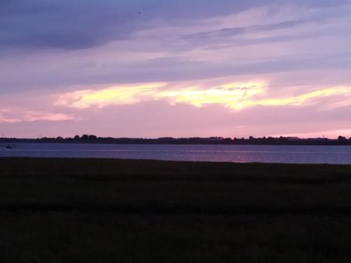 a sunset over the water with a grass field at Philipstère in Sint Philipsland