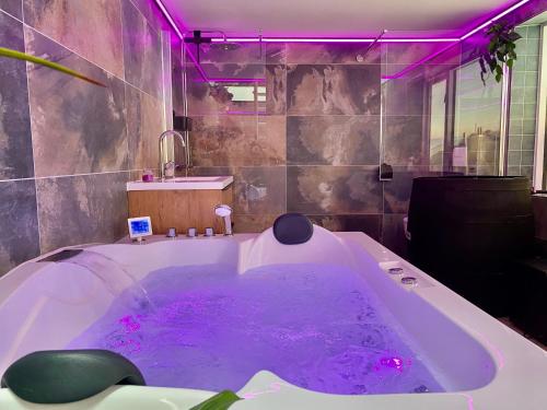 uma casa de banho com uma grande banheira com iluminação roxa em Sommerhaus Glücklich am Meer 2 mit Wellnesszugang em Egmond aan Zee