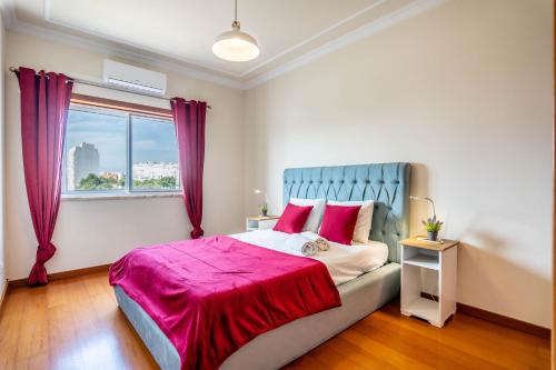 um quarto com uma cama com lençóis vermelhos e uma janela em Relaxing and Central T3 Flat em Portimão