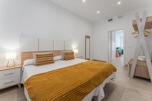 um quarto com uma cama grande e um cobertor amarelo em CMDreams Platinium- Apartamentos turísticos en el centro de Mérida em Mérida