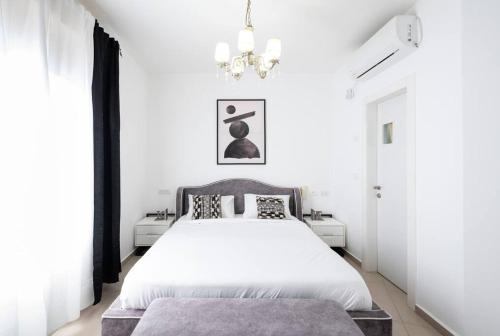 a bedroom with a white bed and a chandelier at Neat 4BR Apt. With Parking/High Floor/Elevator/AC in Rishon LeẔiyyon