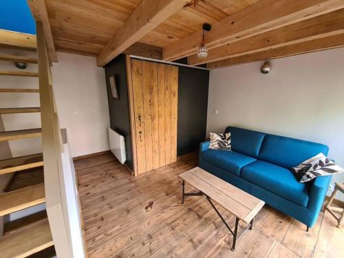 ein Wohnzimmer mit einem blauen Sofa und Holzboden in der Unterkunft Ancien séchoir du 19ème siècle in Saint Die