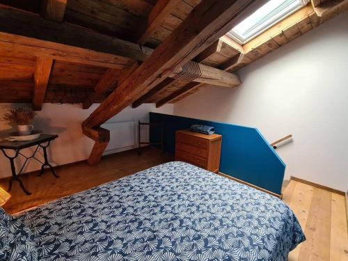 Un dormitorio con una cama azul y una mesa. en Ancien séchoir du 19ème siècle, en Saint-Dié-des-Vosges