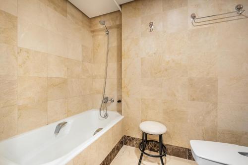 ein Badezimmer mit einer Badewanne, einem WC und einem Stuhl in der Unterkunft Santa Margarita 15-E Apartment Levante Beach in Benidorm