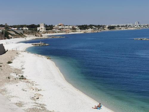 a person sitting on a beach next to the water at Oasi della pace in Bisceglie