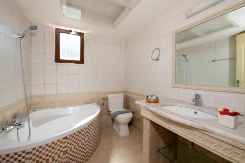 a bathroom with a tub and a toilet and a sink at Villa Alex with private pool and jacuzzi in Prinés