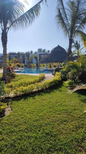 a resort with a swimming pool and palm trees at Depto. frente al mar con Club de Playa in Acapulco