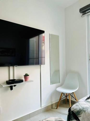a bedroom with a tv and a white chair at Depto. frente al mar con Club de Playa in Acapulco
