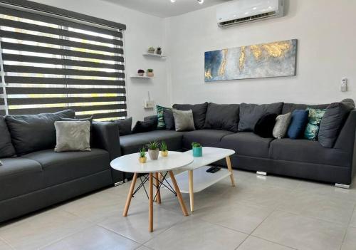 a living room with a black couch and a table at Depto. frente al mar con Club de Playa in Acapulco