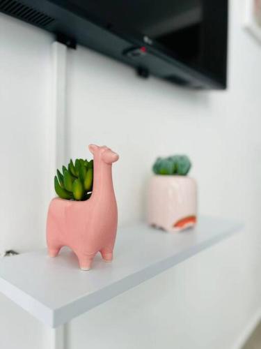 a pink dinosaur toy sitting on a counter with a plant at Depto. frente al mar con Club de Playa in Acapulco