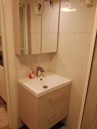 a white bathroom with a sink and a mirror at koselig kjellerleilighet near sentrum in Moss