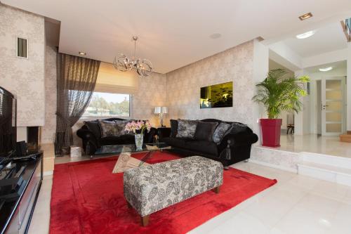 a living room with black furniture and a red rug at Villa Victoria in Gállos