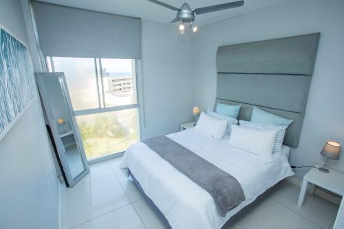 a bedroom with a large white bed and a window at Ballito Vacation Pad Ac Unit With Sea Views in Ballito
