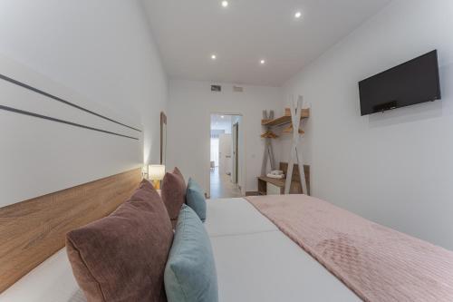 a bedroom with a couch and a tv on the wall at CMDreams Platinium- Apartamentos turísticos en el centro de Mérida in Merida